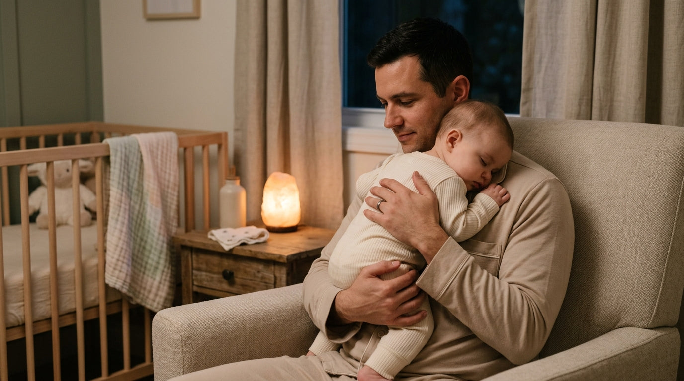 Tired dad holding a crying baby in a dark kitchen at 3 AM.