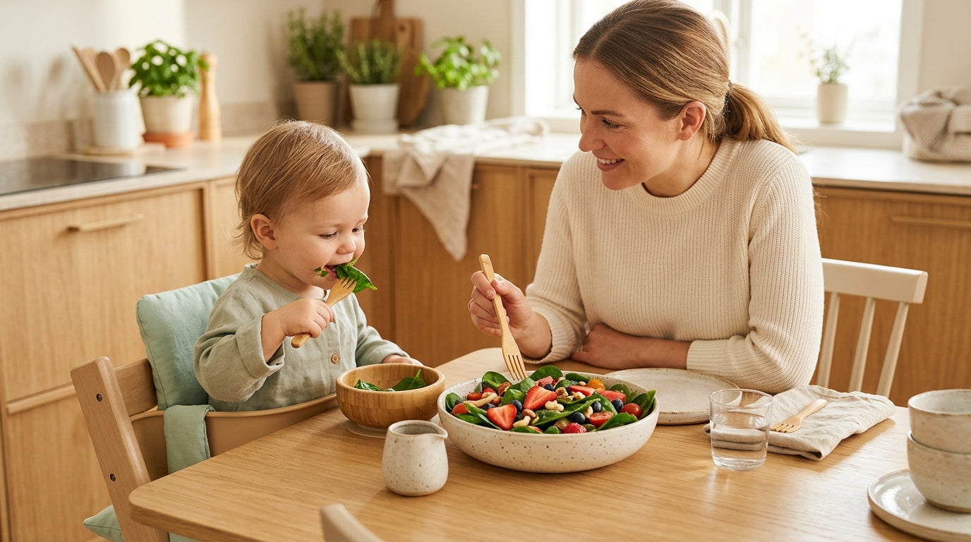 Jess holding a bowl of cooked green puree while her baby reaches for it