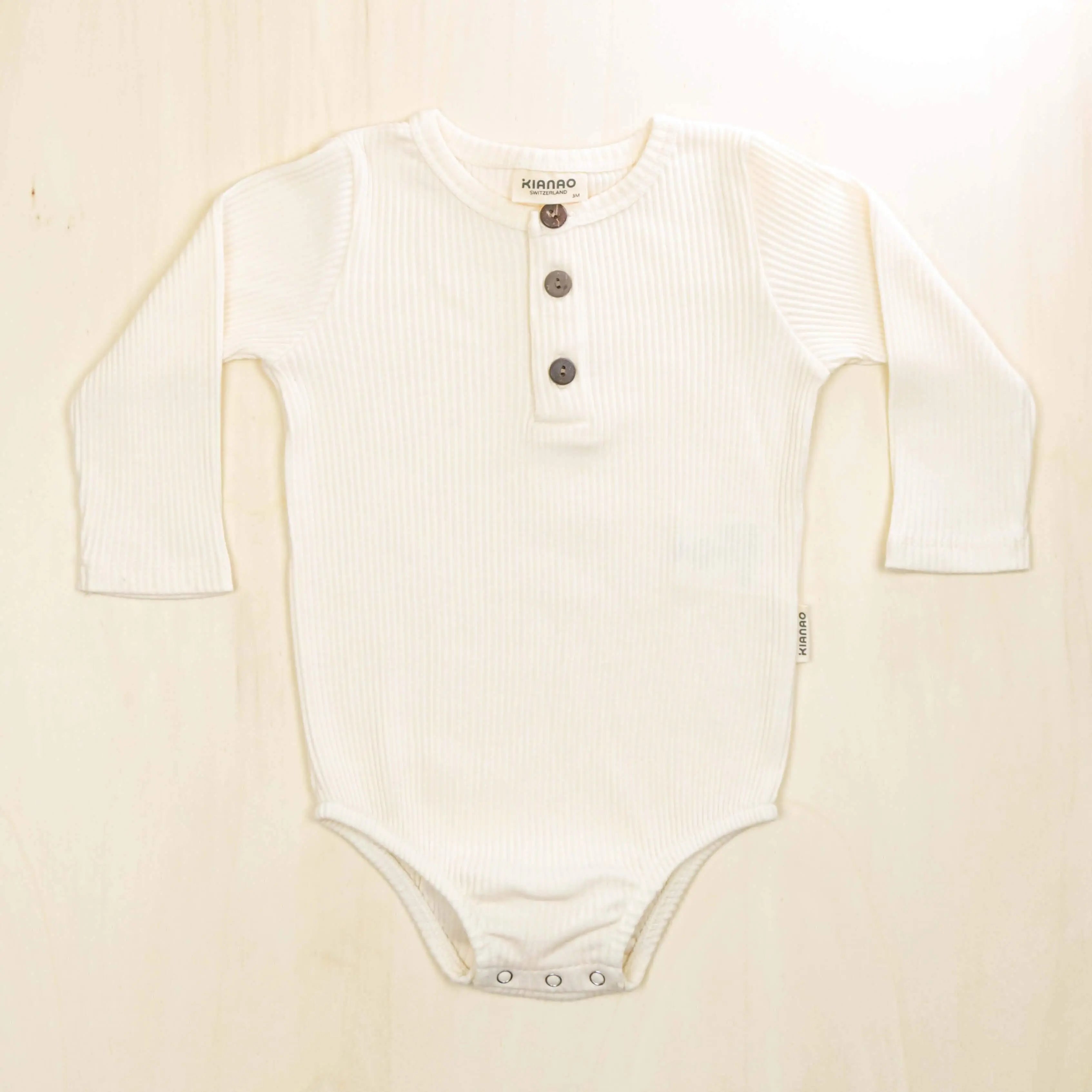 blossom white organic cotton baby bodysuit featuring button front design and cozy long sleeves for layering