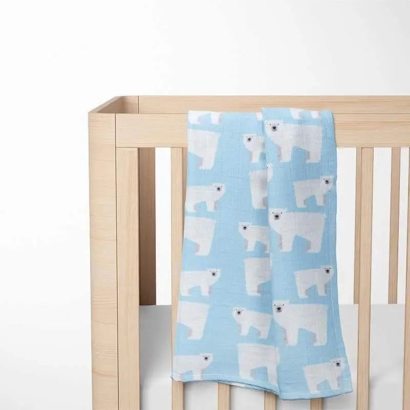light blue organic cotton baby blanket with polar bear pattern displayed in wooden crib showing perfect nursery integration