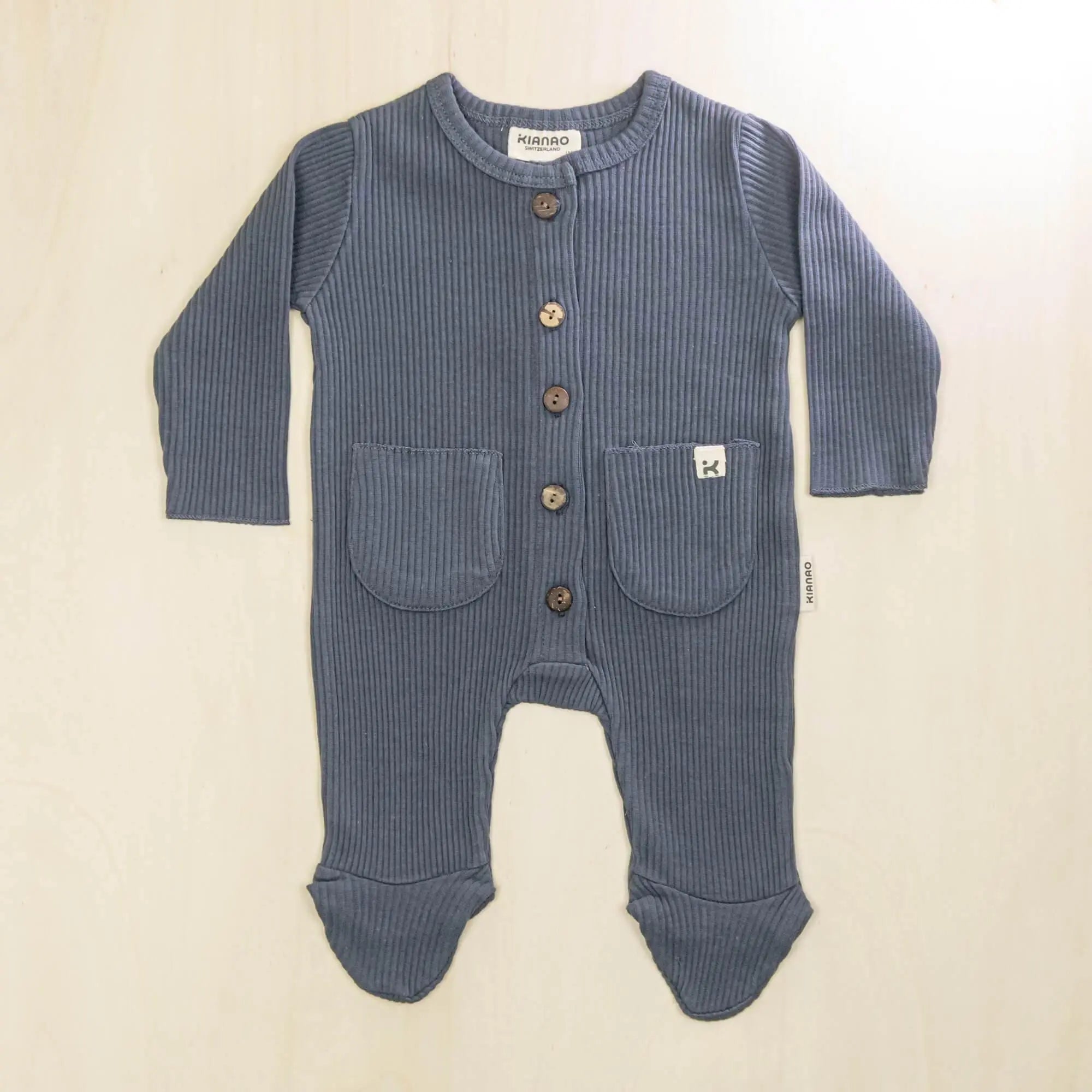indigo blue organic cotton baby romper with button front, integrated feet and two front pockets for newborns to 9 months