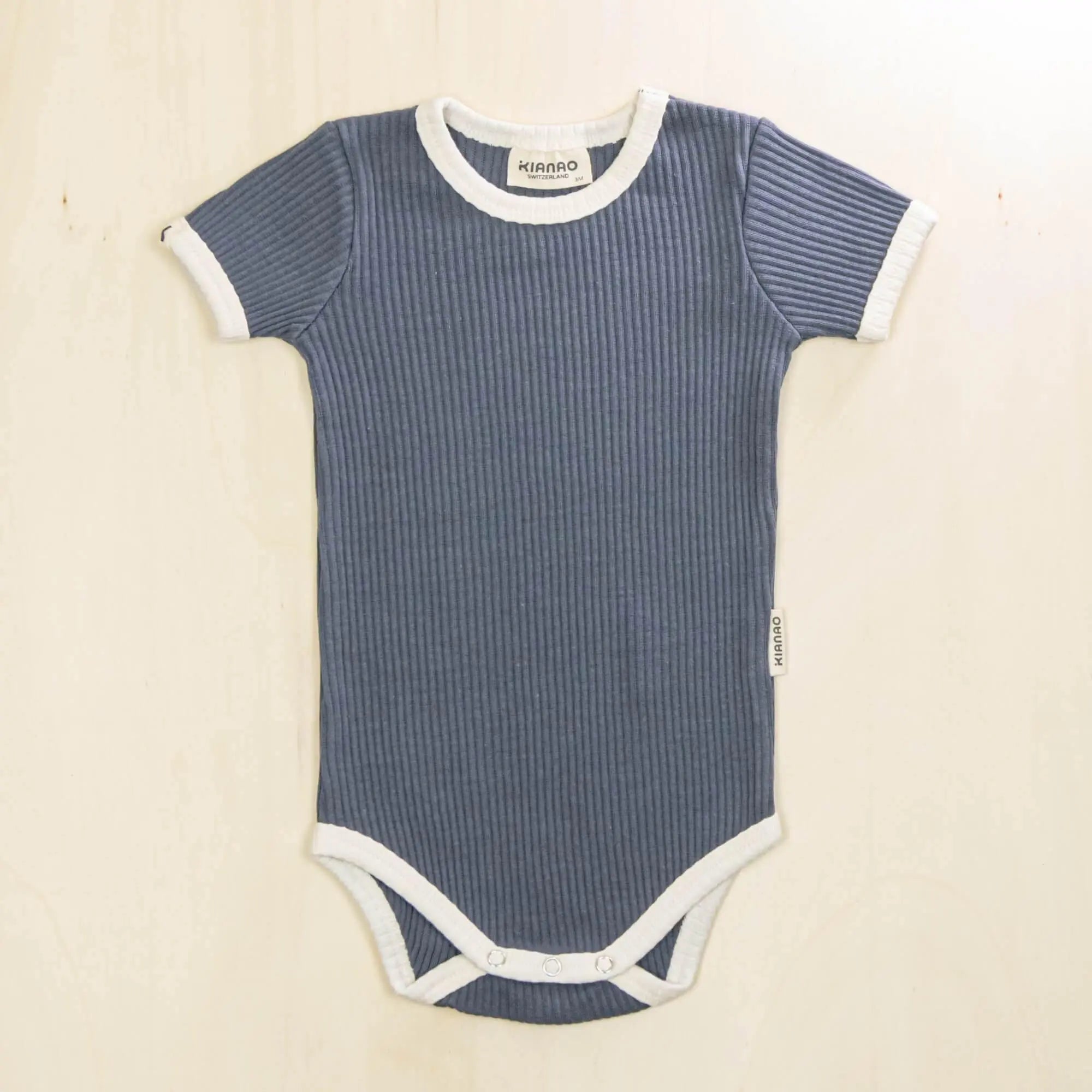 indigo blue short sleeve organic cotton baby bodysuit with white contrast trim and ribbed texture