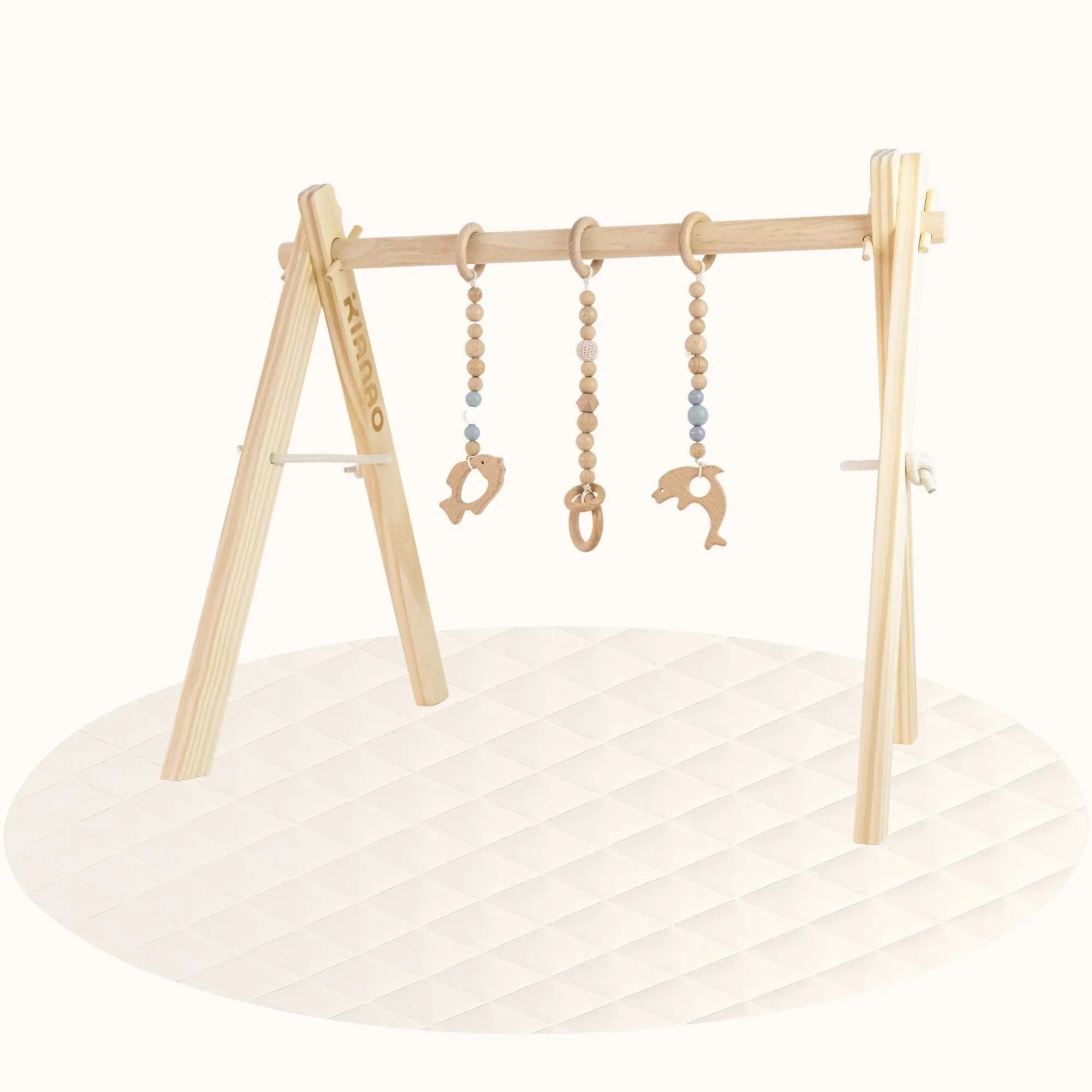 Side view of wooden Fishs Play Gym showing A-frame stability and toy positioning on cream-colored play surface