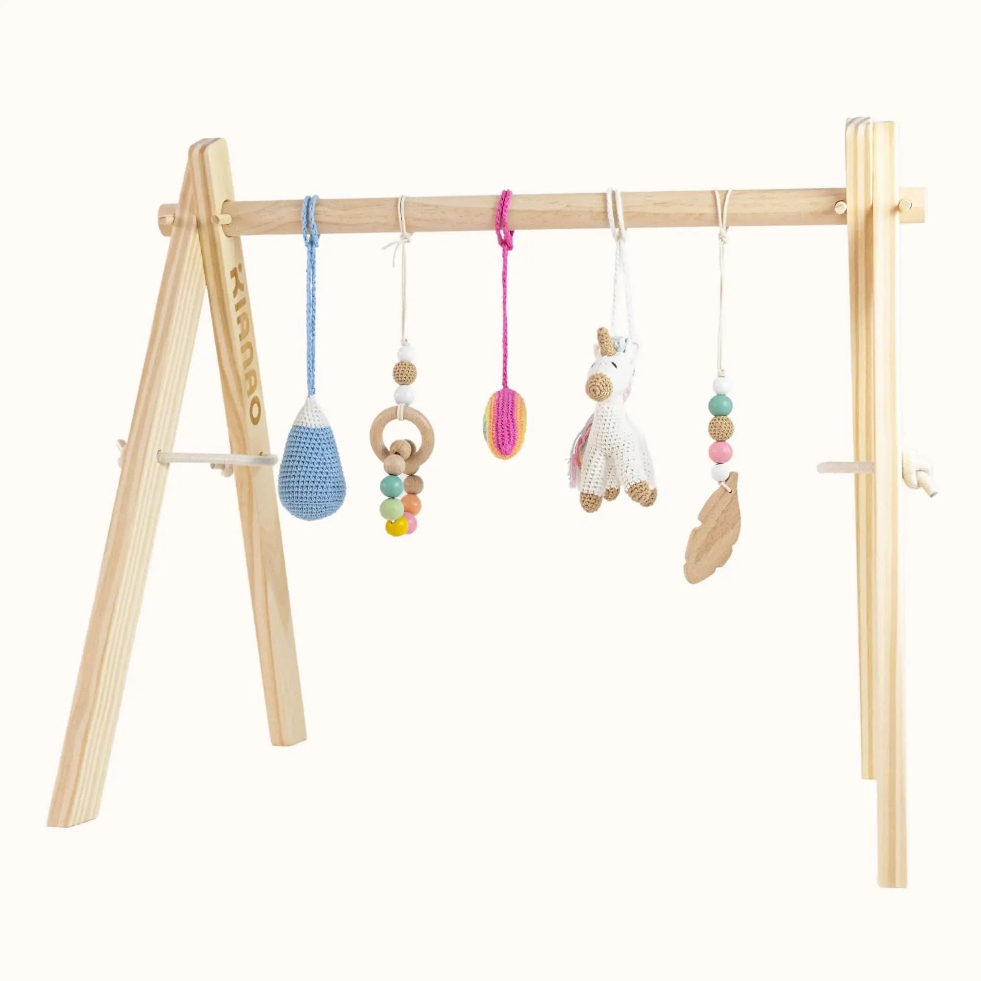 Natural wooden baby gym with colorful crochet hanging toys including unicorn figure, blue teardrop, and wooden rings