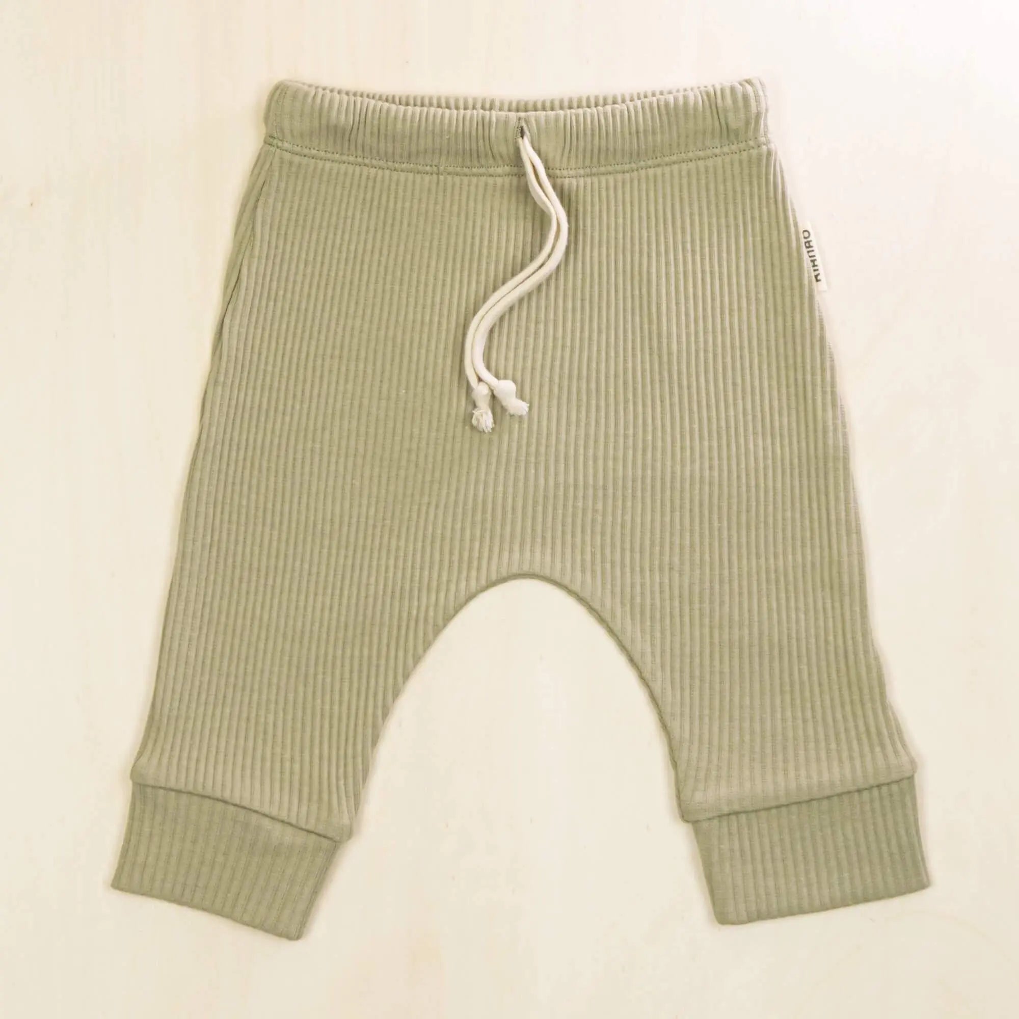 sage green baby pants in breathable organic cotton with white drawstring detail and stretchy ribbed fabric for active babies