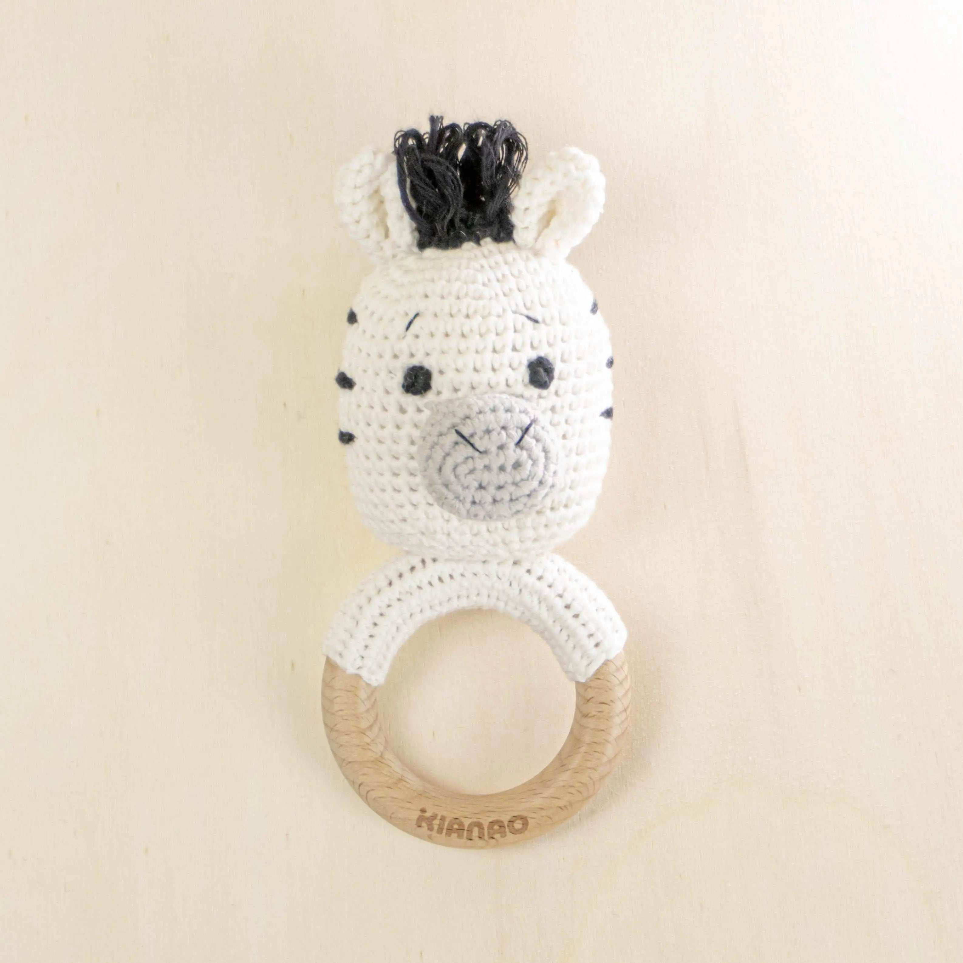 white crochet zebra rattle tooth ring with black details and natural wooden teether for sensory development and teething relief
