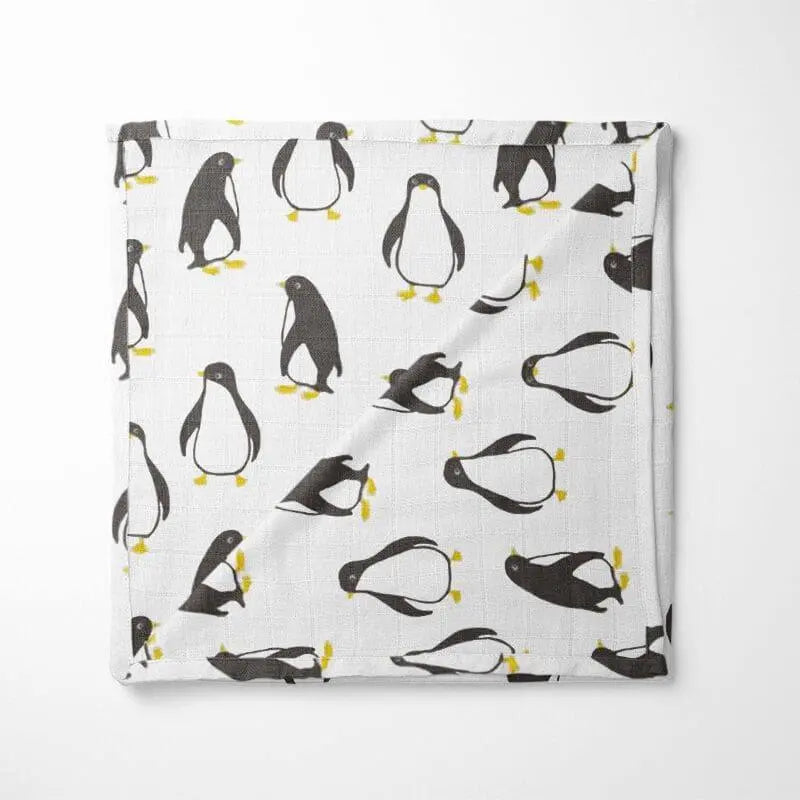 white organic cotton baby blanket with black and yellow penguin pattern double-layer design displayed flat showing playful arctic animals
