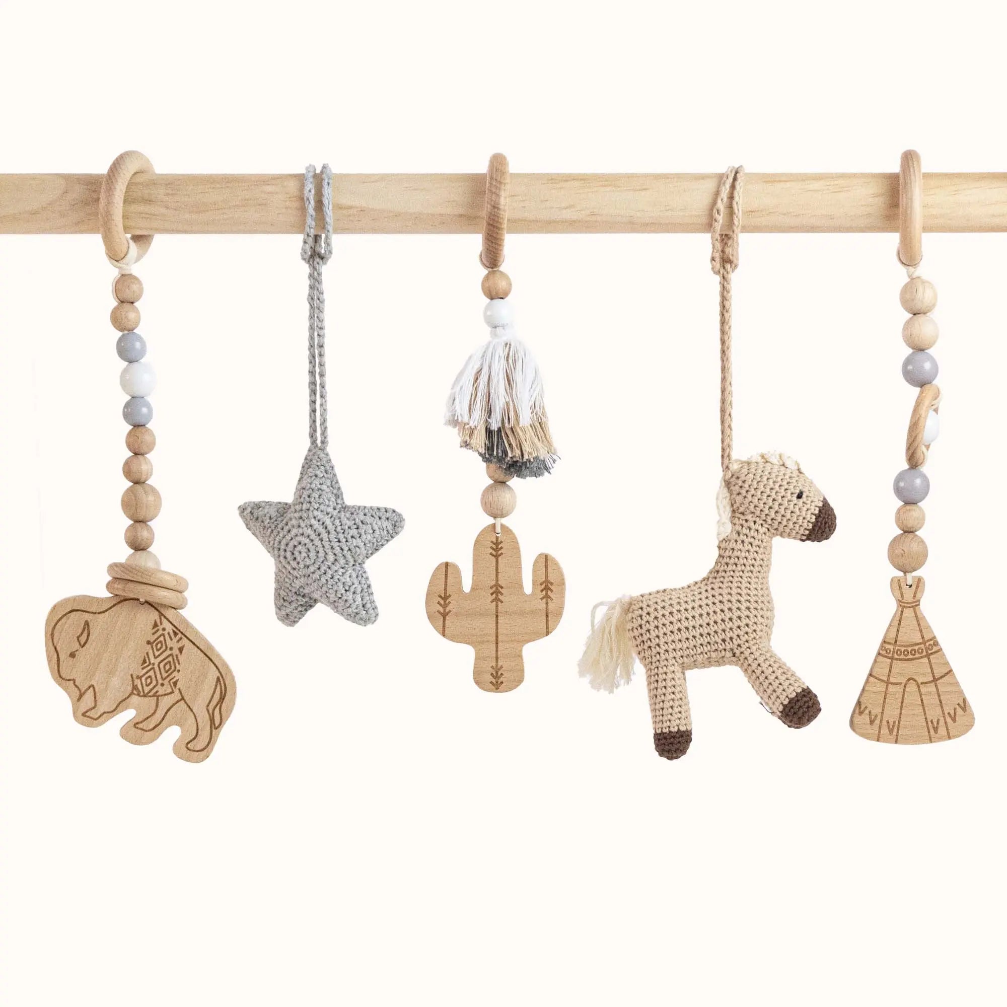 Close-up of Wild Western Play Gym toys showing detailed wooden buffalo carving, grey star, cactus, crocheted horse and teepee