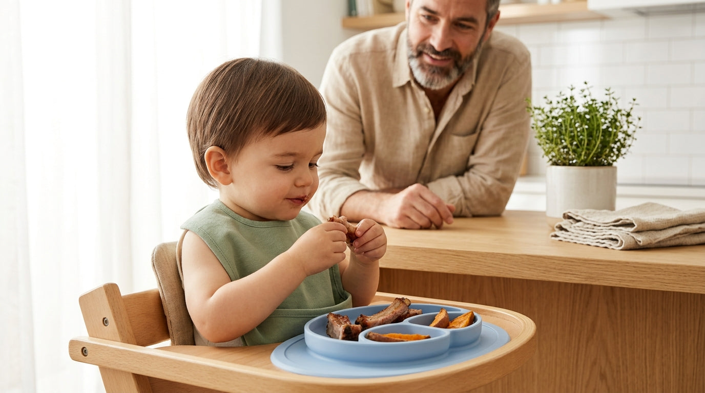 A dad checking the temperature of baked ribs next to a messy baby in a high chair.