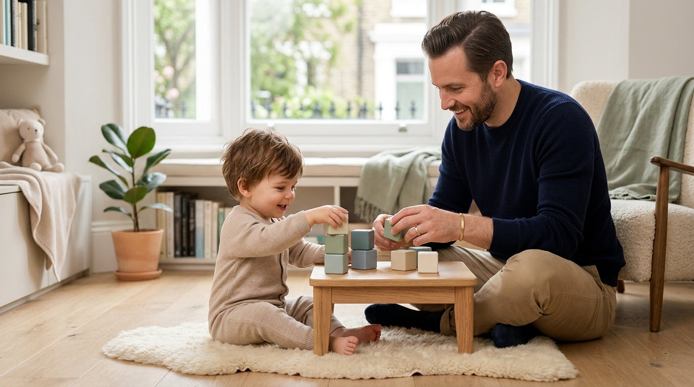 Twin toddlers stacking wooden blocks in a London living room while their dad drinks cold coffee