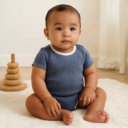 baby wearing indigo blue short sleeve organic cotton baby bodysuit with white contrast trim and ribbed texture