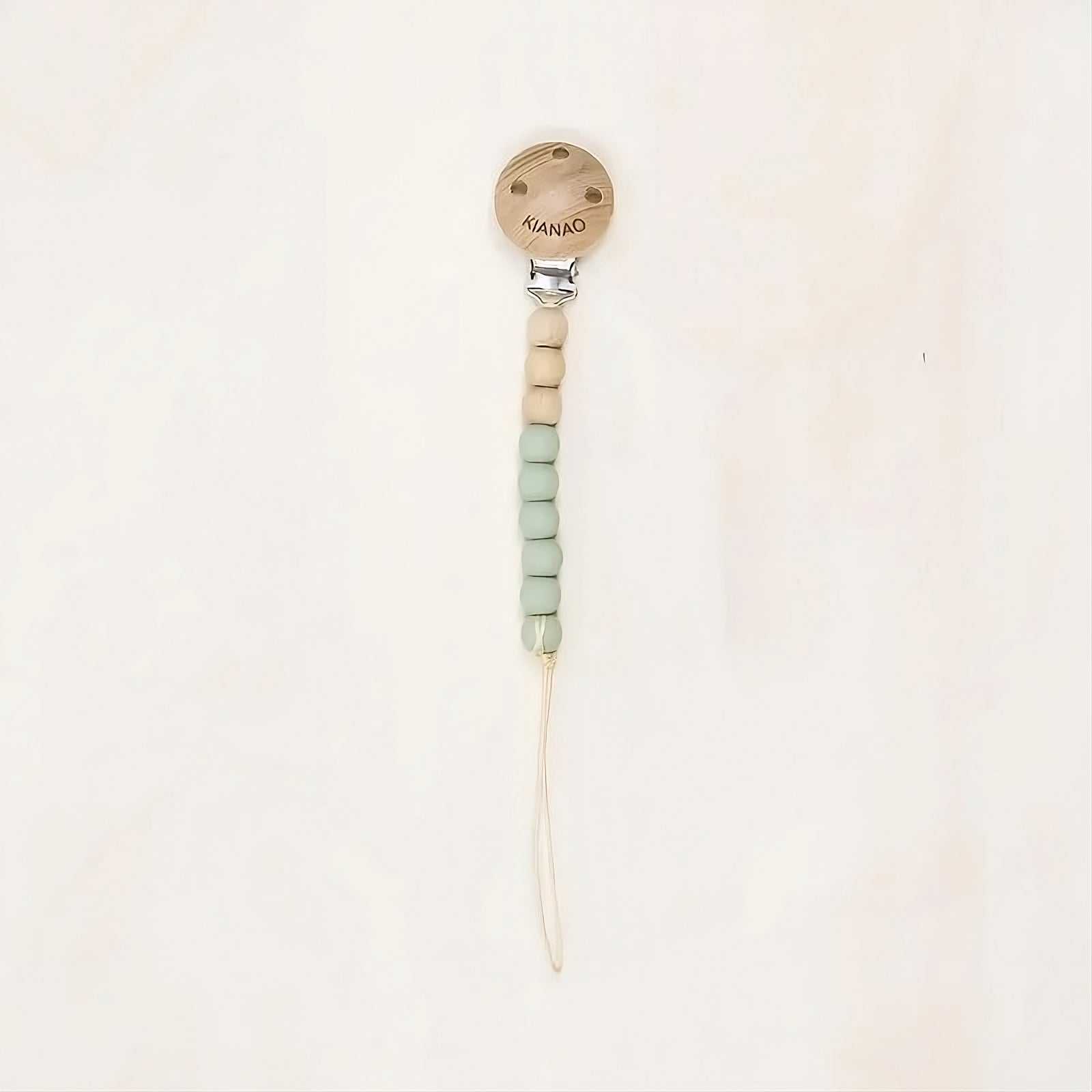 green wooden and silicone pacifier clip with cookie-shaped charm and knotted construction
