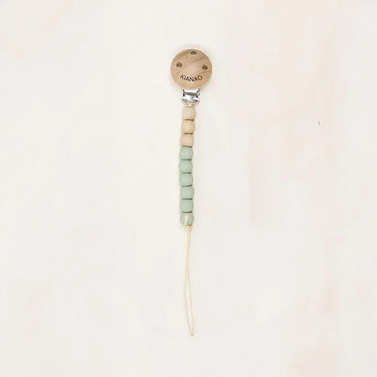 green wooden and silicone pacifier clip with cookie-shaped charm and knotted construction
