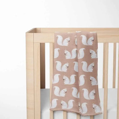 beige organic cotton baby blanket with squirrel pattern displayed in wooden crib showing perfect size and nursery integration