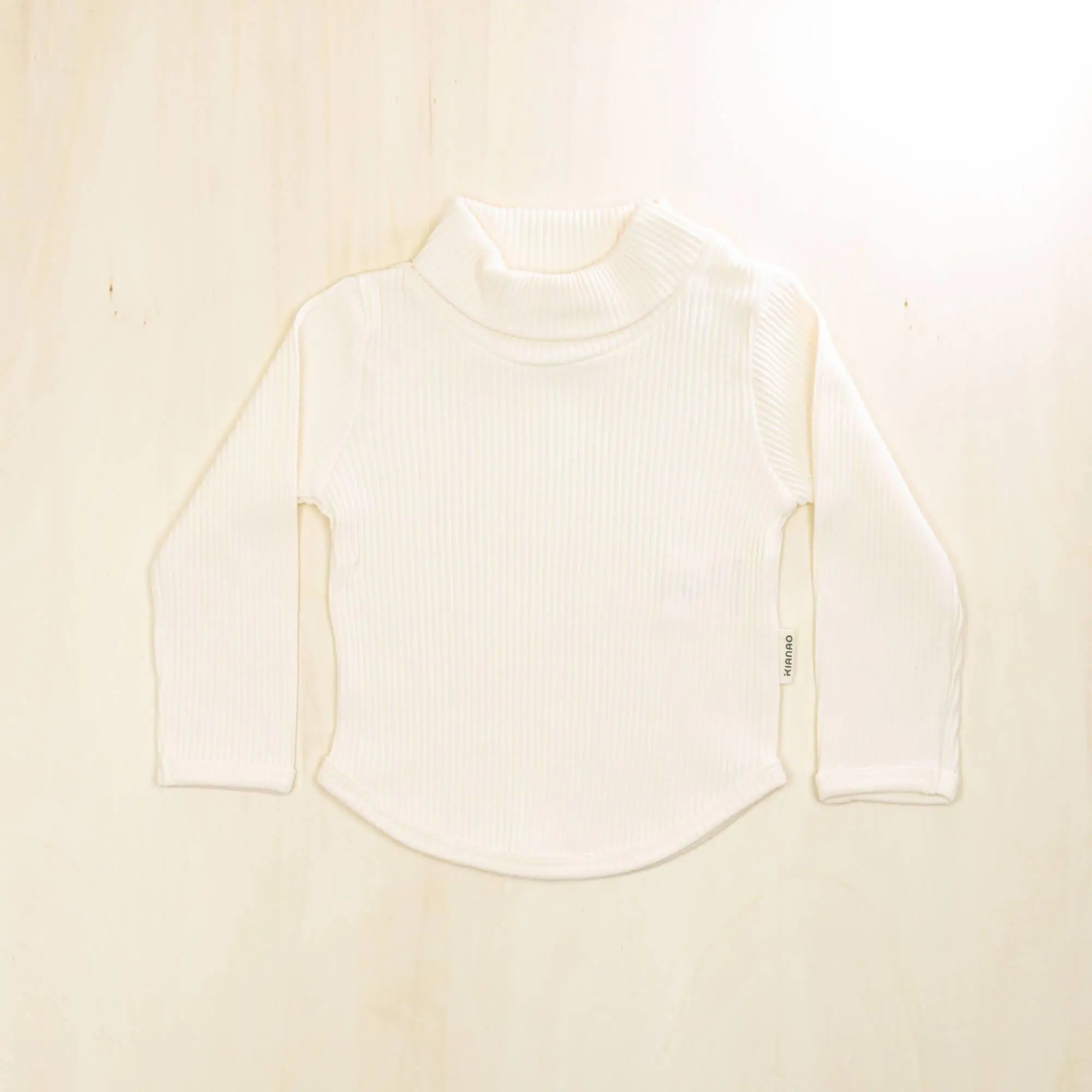 blossom white organic cotton baby turtleneck sweater with curved hem, long sleeves and gentle neck fold for everyday comfort