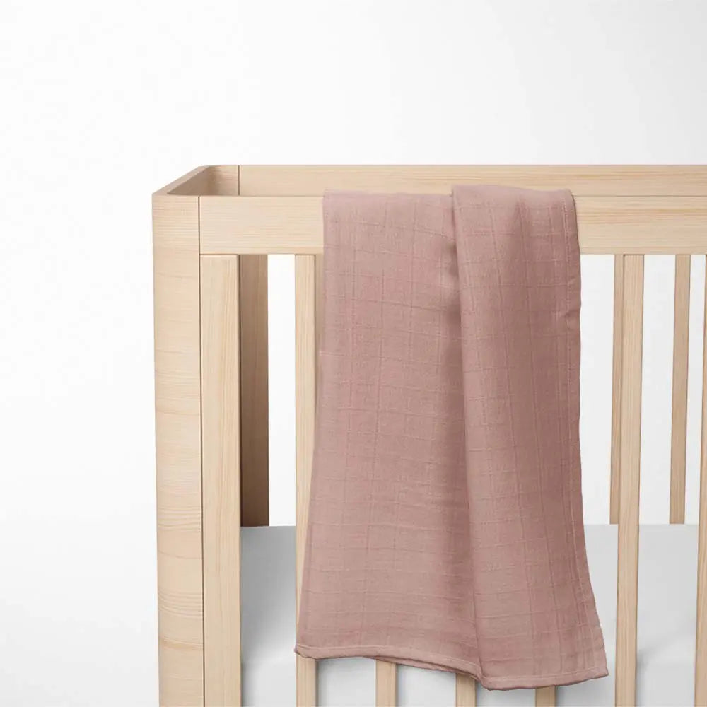 brick red bamboo baby blanket laid out on wooden crib, highlighting the sunny color and lightweight breathable design