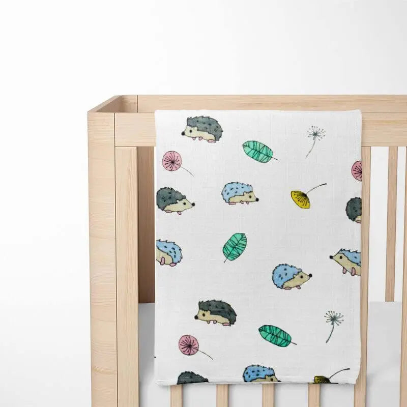 alternative view of hedgehog bamboo baby blanket on crib highlighting the blanket's drape and showing how the pattern enhances nursery aesthetics