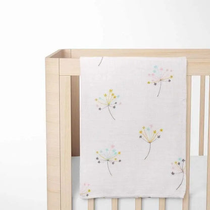 cream organic bamboo baby blanket with floral pattern displayed on crib showing size and nursery integration