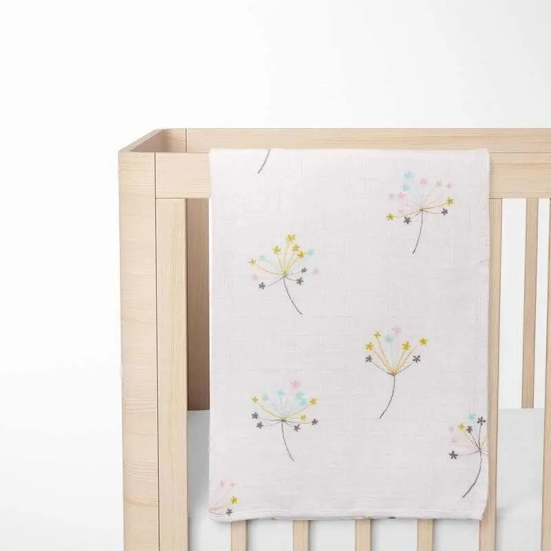 cream organic bamboo baby blanket with floral pattern displayed on crib showing size and nursery integration