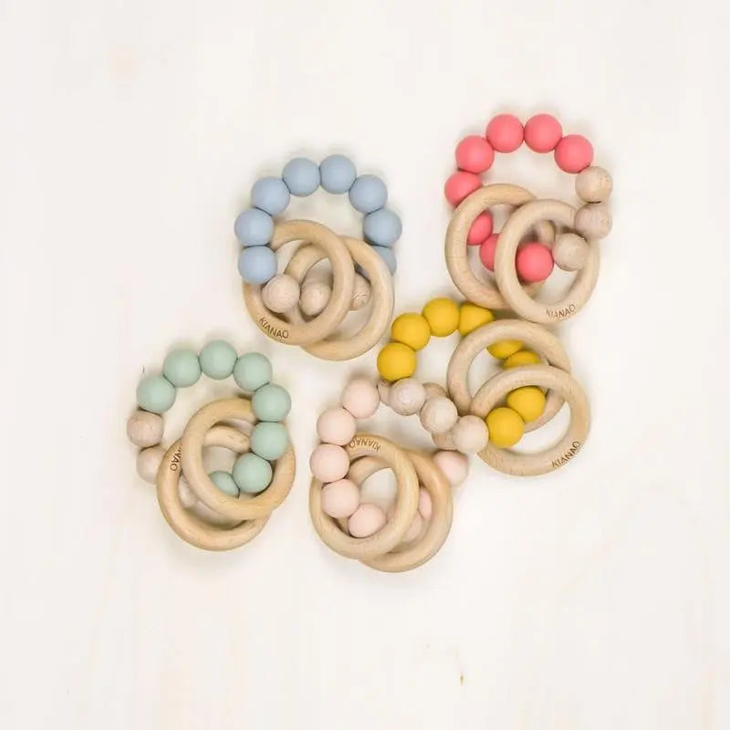 collection of handmade wooden teething rings with colorful silicone beads in mint yellow red and blue natural baby teethers