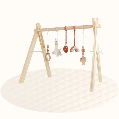 Side view of wooden Lama with Strawberry Play Gym showing A-frame structure with hanging desert-themed toys