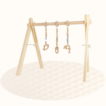Side view of wooden Fishs Play Gym showing A-frame stability and toy positioning on cream-colored play surface