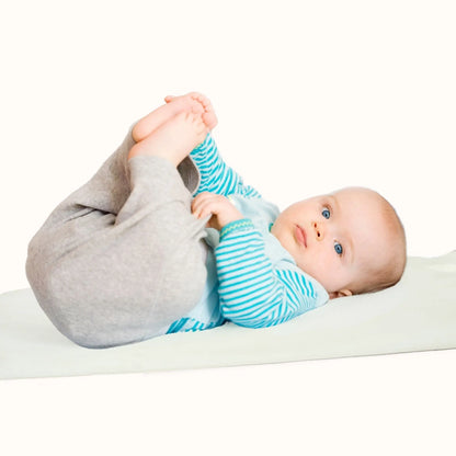 baby lying on oat cream waterproof changing mat showing soft vegan leather surface
