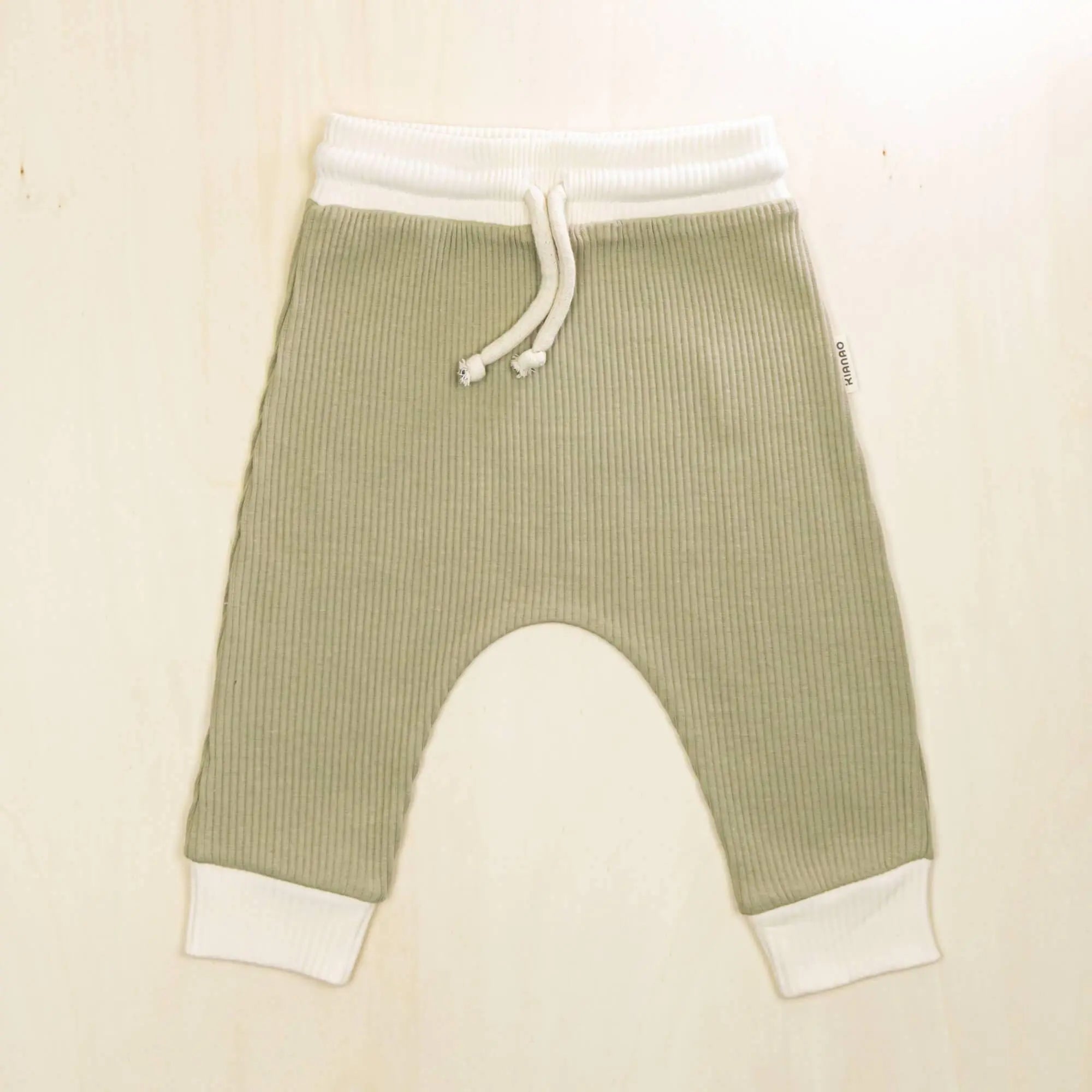 sage green organic cotton baby pants with white contrast trim, drop-crotch jogger style with room for cloth or disposable diapers