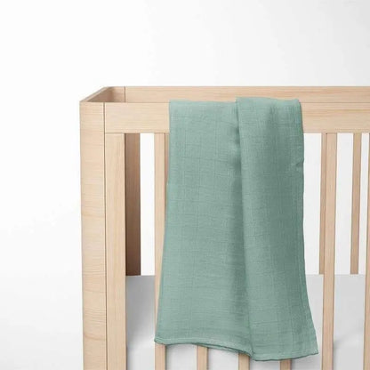 sage green bamboo baby blanket displayed on wooden crib, highlighting the breathable texture and natural color