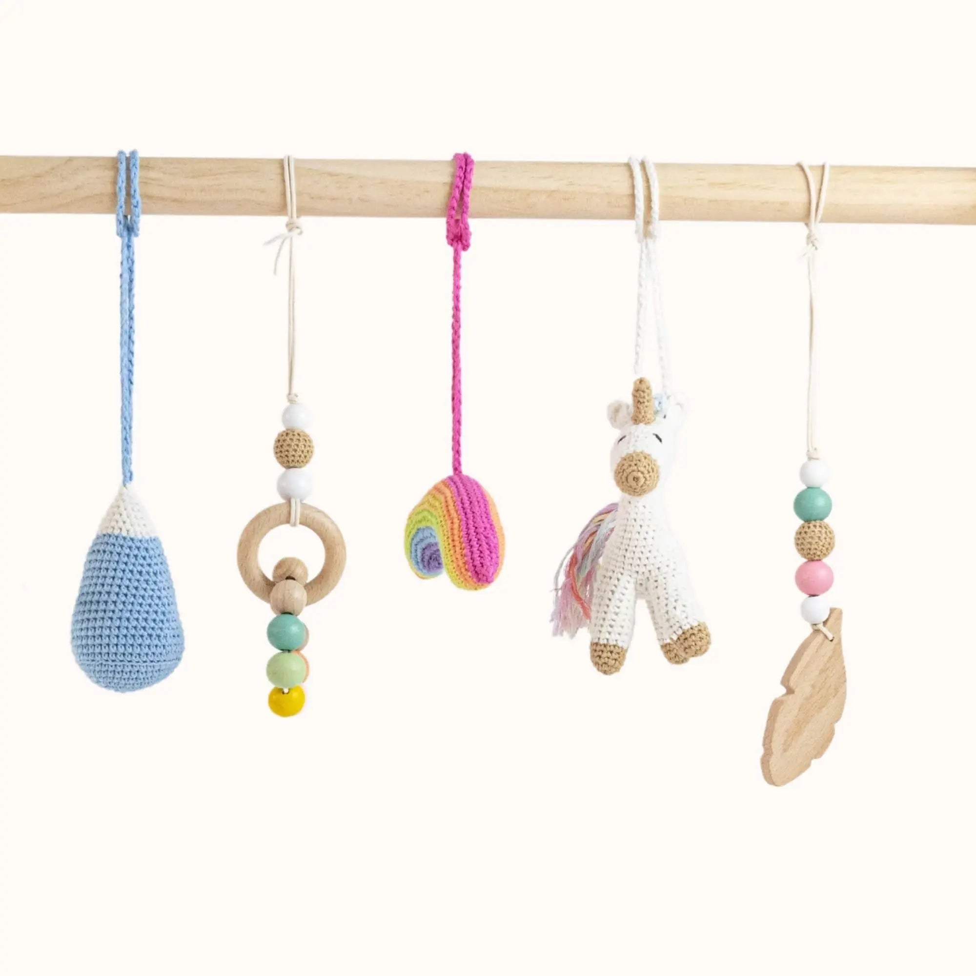 Close-up of Unicorn Play Gym handcrafted toys showing detailed crochet unicorn, blue teardrop, pink ball, and wooden rings