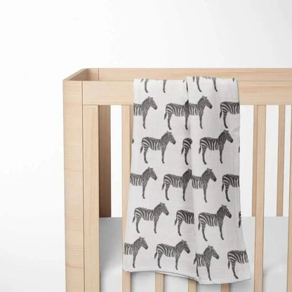 folded white baby blanket with black zebra pattern displayed on wooden crib showing double-layer organic cotton construction