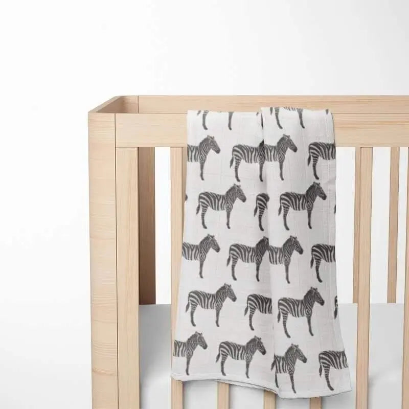 folded white baby blanket with black zebra pattern displayed on wooden crib showing double-layer organic cotton construction