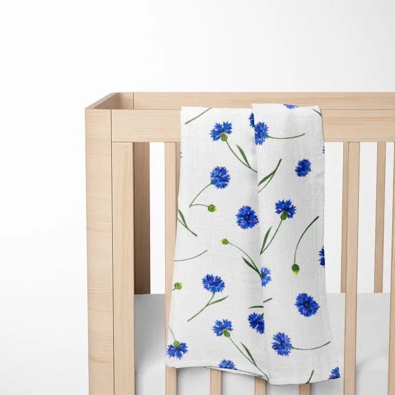 white bamboo baby blanket with blue floral pattern displayed on crib showing perfect size for infant sleep