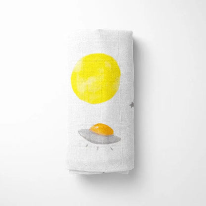 rolled white bamboo baby blanket showing yellow planet pattern, compact for travel and storage