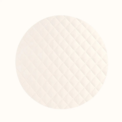 Close-up of cream-colored quilted vegan playmat showing soft texture contrasting with natural wood elements