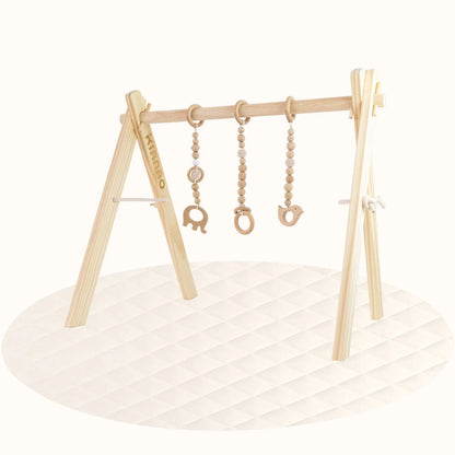Side view of all-wood baby gym showing A-frame structure with hanging animal-shaped wooden toys